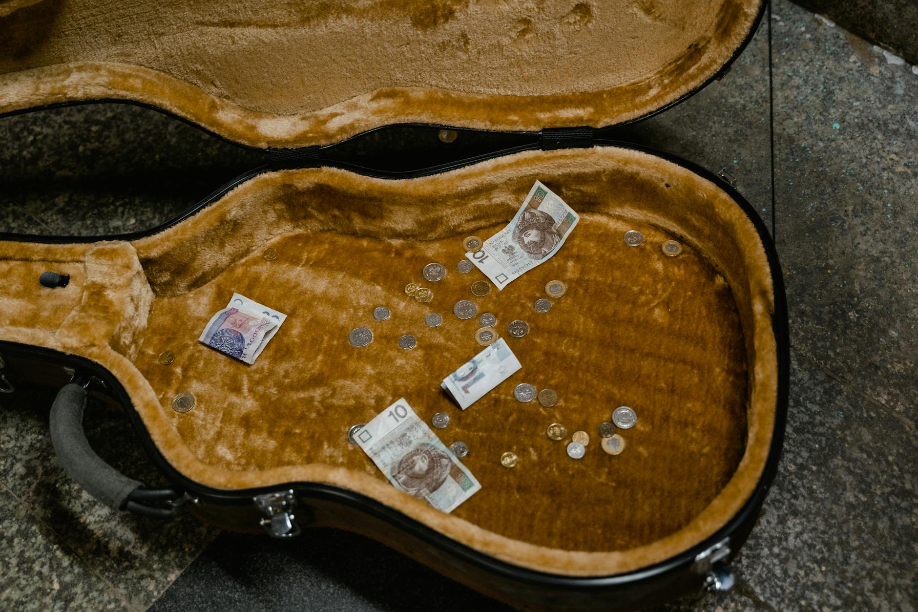 Open guitar case with change and dollar bills